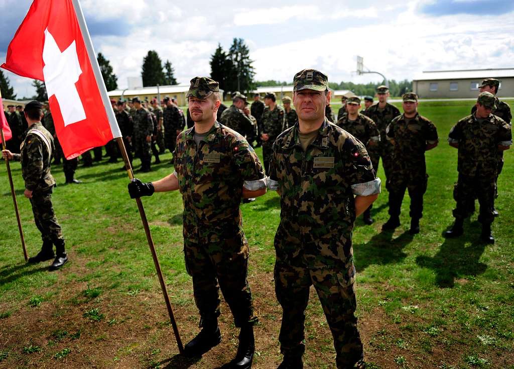 Die Schweiz verteidigt sich seit Jahrhunderten allein – mit einer Armee, die fast vollständig aus Wehrpflichtigen besteht und deren Bild zwischen Wehrhaftigkeit und Feierabenddienst schwankt. Seit dem russischen Angriff auf die Ukraine richtet sich die Truppe wieder auf die Landesverteidigung aus und trifft dabei auf drei Jahrzehnte Substanzverlust, Ausrüstungslücken und eine blockierte Finanzierung. Eine Bestandsaufnahme von Auftrag, Struktur, Material und den Grenzen des Milizmodells.